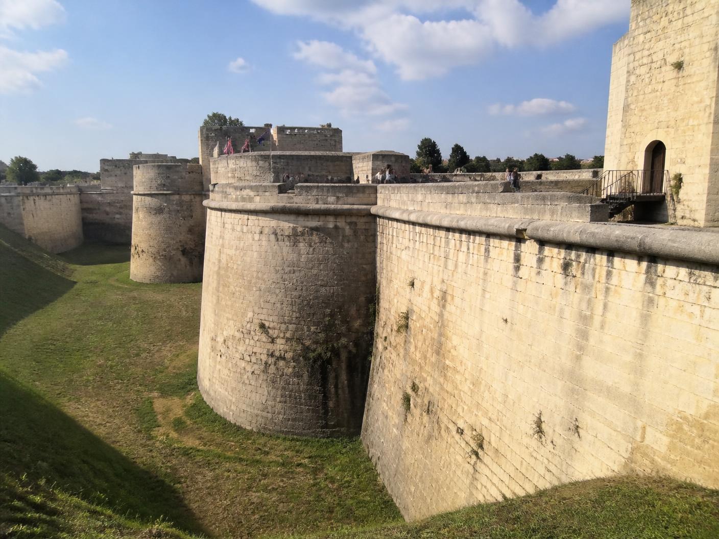 Illustration du château ducal de Caen : remparts de pierre claire, pelouses et promeneurs au cœur de la ville