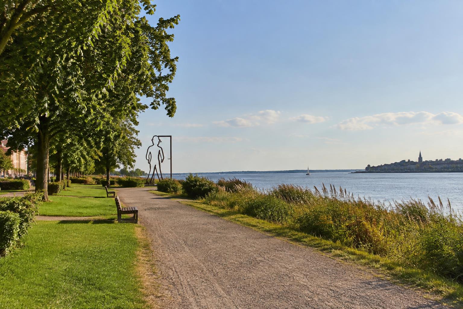 Promenade de bord d'estuaire à Paimbœuf : allée bordée d'arbres, bancs et roselières face à la Loire