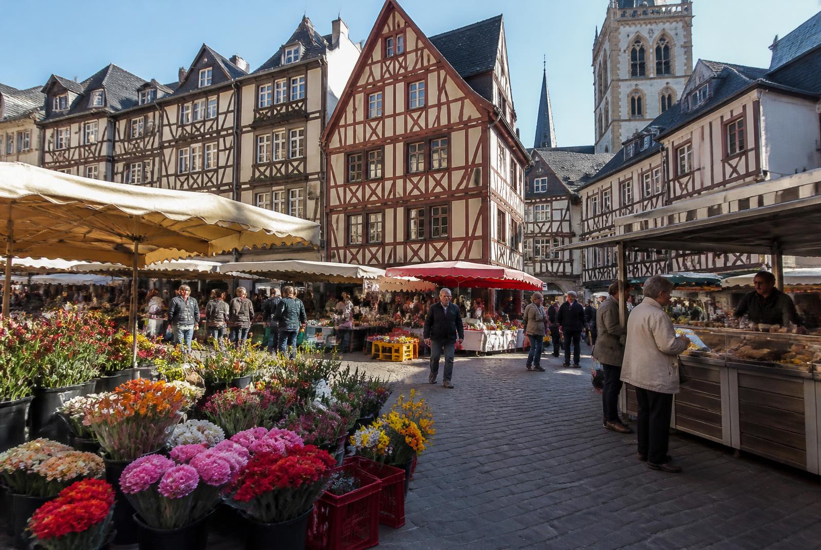 Illustration d'un marché rouennais entouré de maisons à pans de bois, étals de fleurs et passants